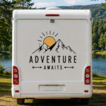 Sticker montagne avec soleil et texte Adventure Awaits sur un véhicule utilitaire