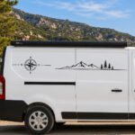 Sticker représentant une boussole et une chaîne de montagnes avec des arbres sur un véhicule utilitaire