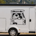 Sticker caméléon portant des lunettes de soleil au volant d'un van avec une planche de surf sur le toit tenant une tasse