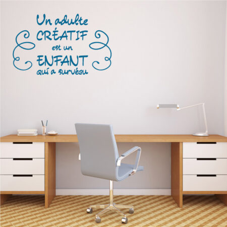 Sticker mural citation "Un adulte créatif est un enfant qui a survécu" en lettres bleues sur mur blanc dans un bureau moderne